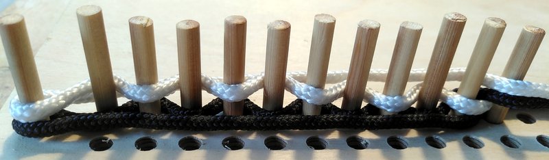 12 pegs with black and white threads woven between them