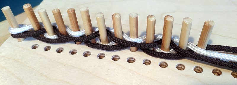 13 pegs with black and white threads woven between them