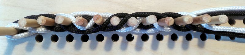 13 pegs with black and white threads woven between them