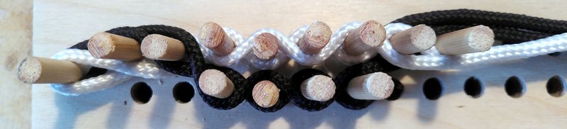 Wooden pegs with black and white threads woven between them